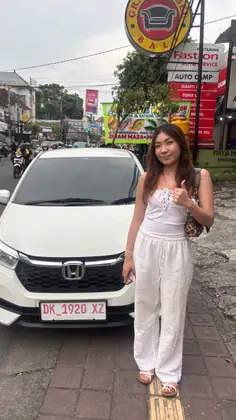 A customer with our white Honda Brio on a street in Denpasar